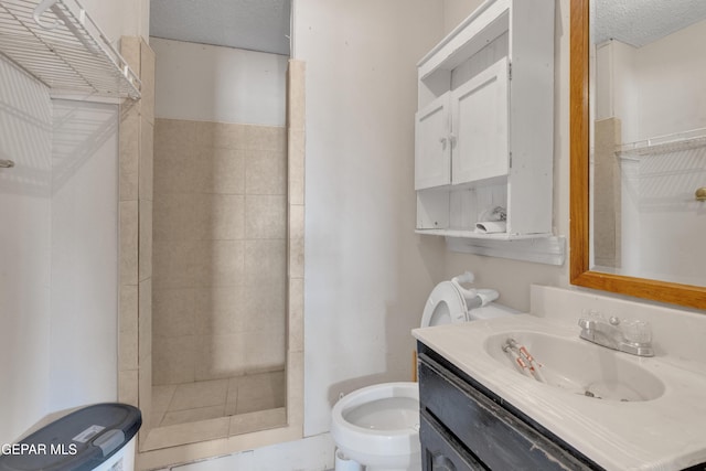 full bath featuring toilet, vanity, a shower stall, and a textured ceiling