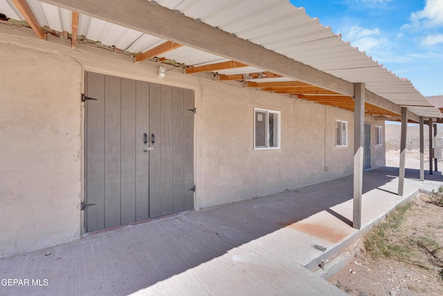 view of exterior entry with stucco siding and a patio