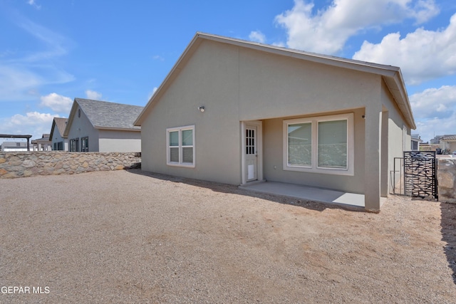 rear view of house featuring a patio area and stucco siding