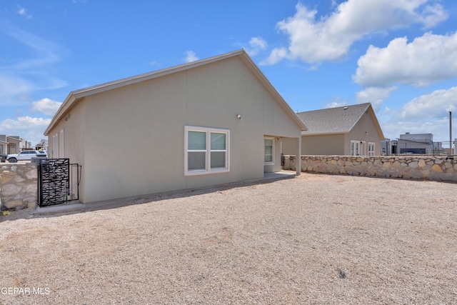 rear view of house with stucco siding and fence