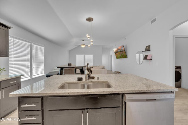 kitchen featuring washer / clothes dryer, a sink, open floor plan, a ceiling fan, and stainless steel dishwasher