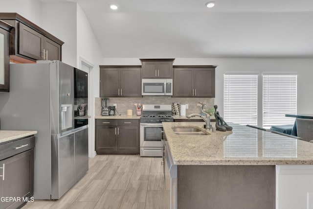 kitchen featuring dark brown cabinetry, vaulted ceiling, appliances with stainless steel finishes, a sink, and decorative backsplash