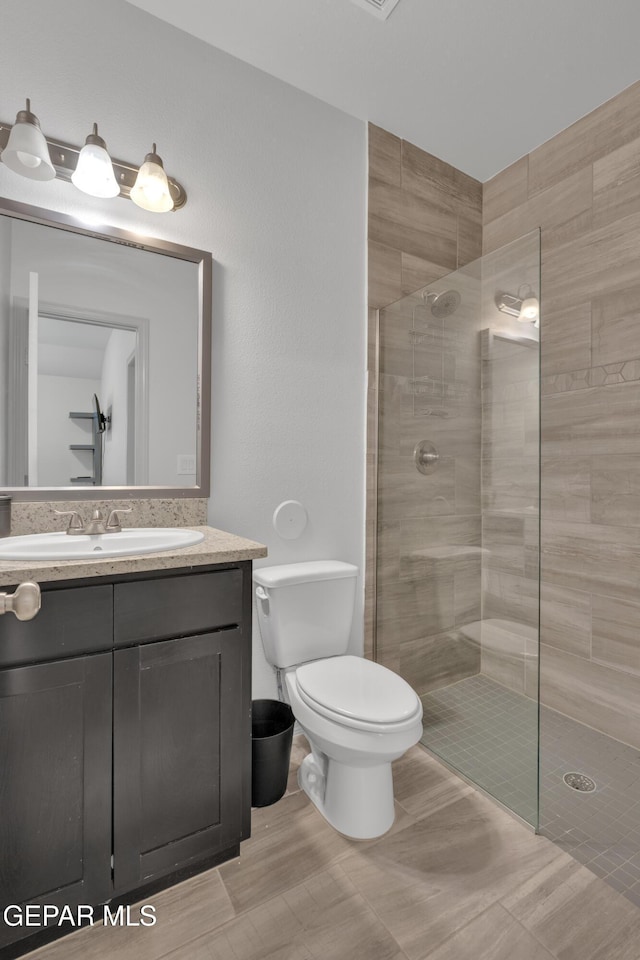 bathroom featuring toilet, a walk in shower, and vanity