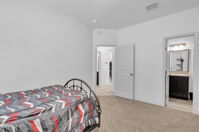 bedroom featuring baseboards, light colored carpet, ensuite bath, and visible vents