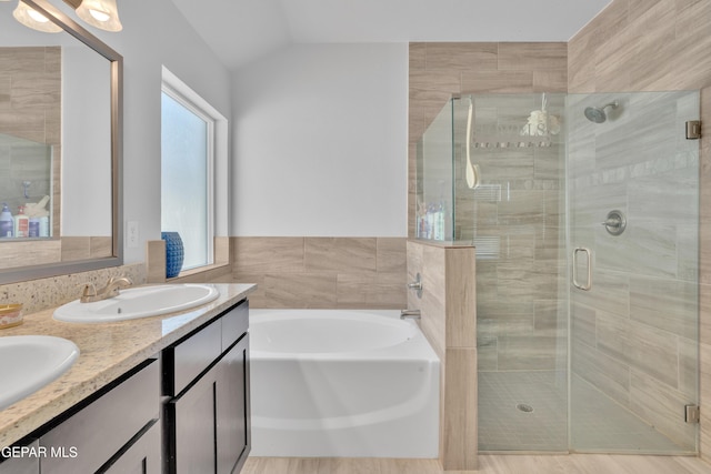bathroom with a sink, double vanity, a shower stall, lofted ceiling, and a garden tub