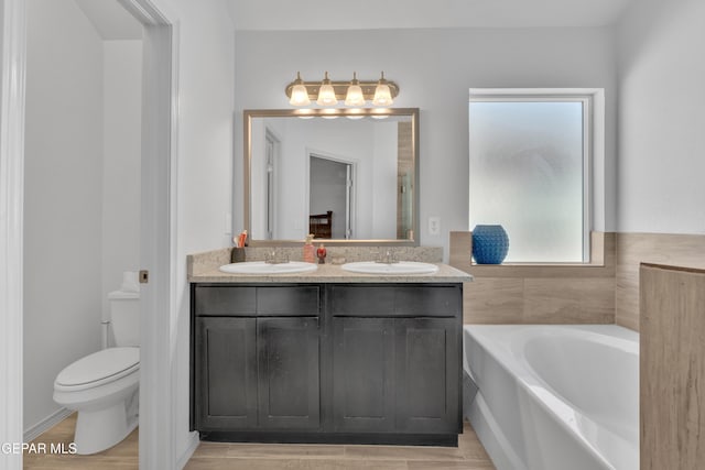 bathroom featuring a sink, toilet, double vanity, and a garden tub