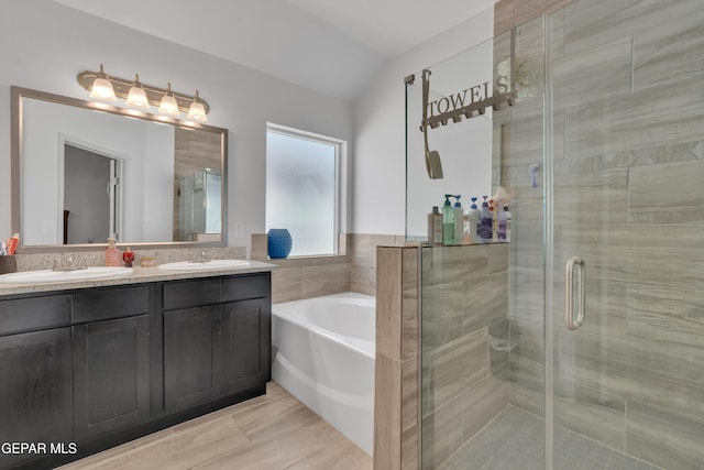 bathroom featuring a stall shower, a garden tub, double vanity, and a sink