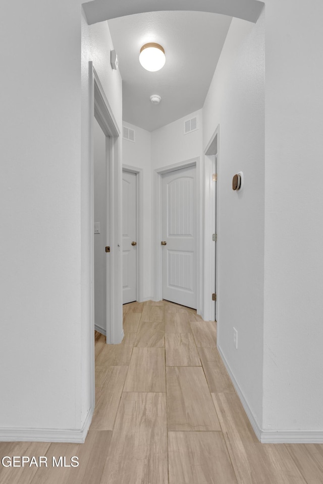 hallway with visible vents and baseboards
