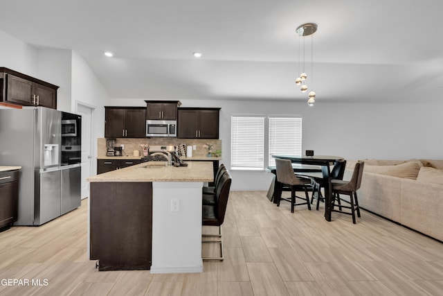 kitchen featuring tasteful backsplash, a sink, appliances with stainless steel finishes, dark brown cabinetry, and vaulted ceiling