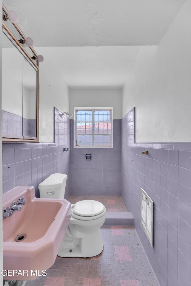 2413 Copper Ave Unit 79930, El Paso, TX 79930 - full bath with tile walls, toilet, a sink, a wainscoted wall, and a tile shower