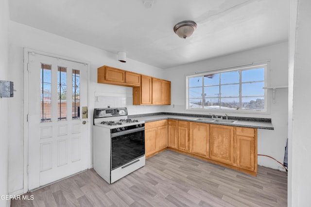 2413 Copper Ave Unit 79930, El Paso, TX 79930 - kitchen featuring gas range gas stove, a sink, dark countertops, and light wood-style floors