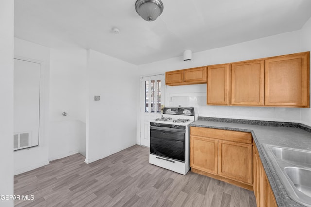 2413 Copper Ave Unit 79930, El Paso, TX 79930 - kitchen featuring white gas range, a sink, dark countertops, and light wood-type flooring