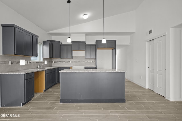 2217 Tony Harper St, El Paso, TX 79938 - kitchen with wood tiled floors, decorative backsplash, a kitchen island, hanging light fixtures, and high vaulted ceiling