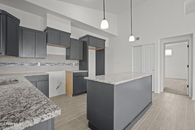 2217 Tony Harper St, El Paso, TX 79938 - kitchen featuring a kitchen island, decorative backsplash, a towering ceiling, wood tiled floors, and pendant lighting
