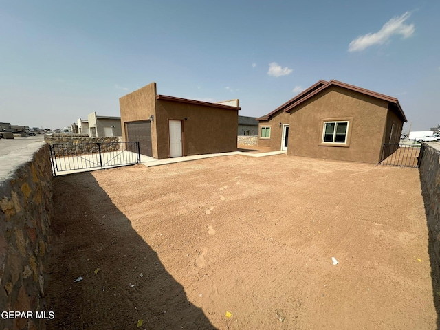 2237 Tony Harper St, El Paso, TX 79938 - rear view of house featuring a gate, stucco siding, an outdoor structure, fence, and a garage