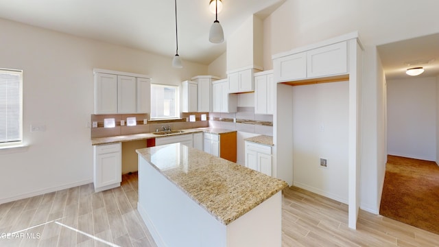2237 Tony Harper St, El Paso, TX 79938 - kitchen with light stone counters, a sink, a kitchen island, wood finish floors, and white cabinets