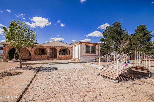back of property featuring brick siding and a gate