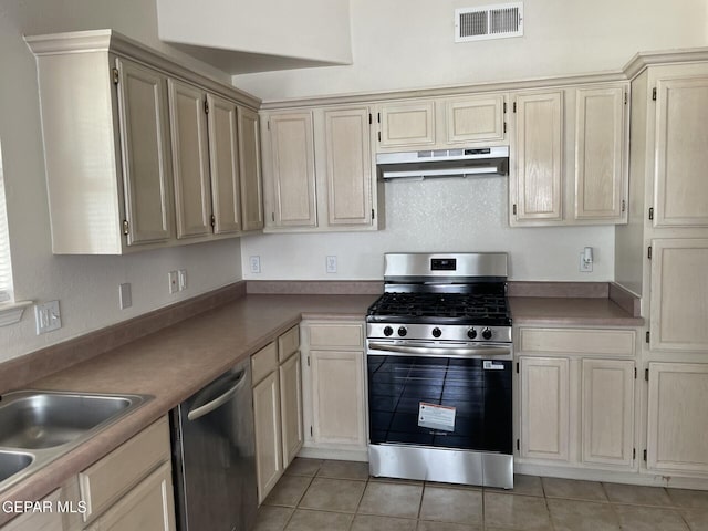12340 Tierra Madre Rd, El Paso, TX 79938 - kitchen with stainless steel appliances, under cabinet range hood, light tile patterned floors, a sink, and cream cabinetry