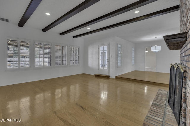 4945 Vista Grande Cir, El Paso, TX 79922 - unfurnished living room featuring beamed ceiling, visible vents, a brick fireplace, a notable chandelier, and wood finished floors