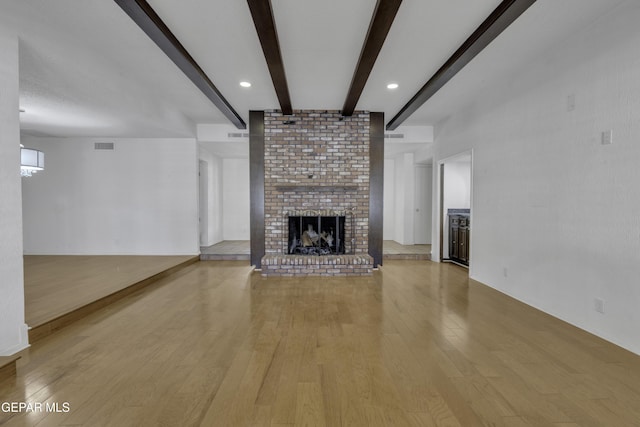 4945 Vista Grande Cir, El Paso, TX 79922 - unfurnished living room featuring beam ceiling, light wood-style floors, a fireplace, and visible vents