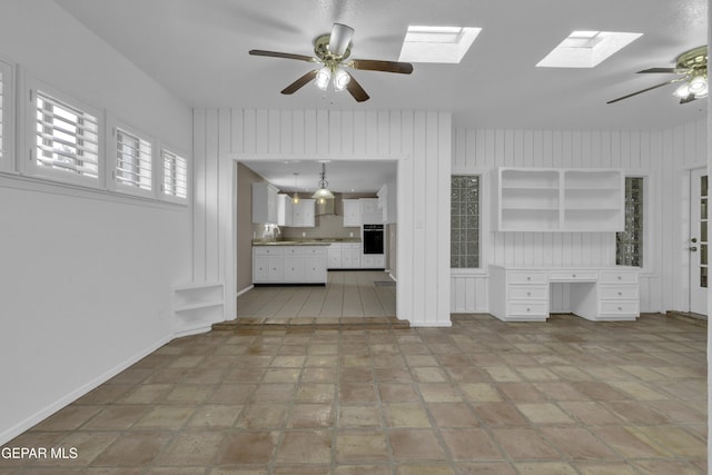 4945 Vista Grande Cir, El Paso, TX 79922 - unfurnished living room featuring built in desk, baseboards, a sink, a skylight, and a ceiling fan