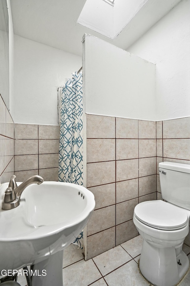 9005 Electra Dr, Canutillo, TX 79835 - full bathroom featuring toilet, a skylight, a sink, tile walls, and tile patterned floors