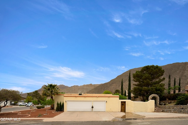 view of front of property with a mountain view, driveway, a garage, and stucco siding