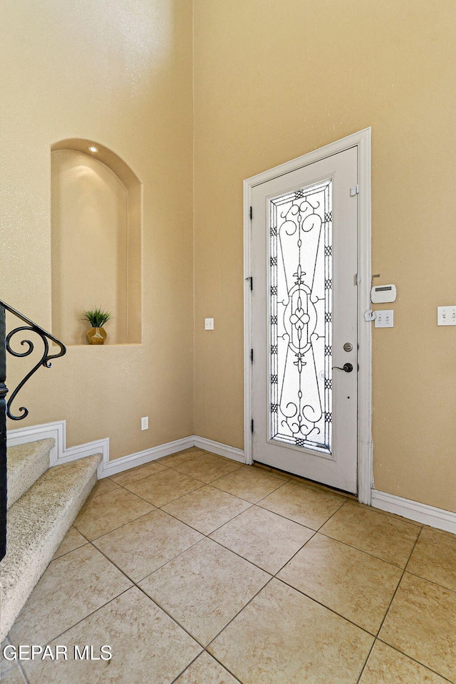 foyer with baseboards, stairway, a high ceiling, and tile patterned flooring
