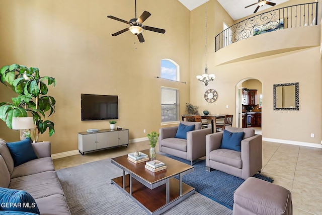 living area with arched walkways, ceiling fan, baseboards, and tile patterned flooring