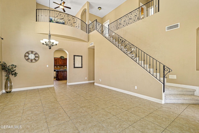 interior space featuring stairs, baseboards, ceiling fan with notable chandelier, visible vents, and arched walkways
