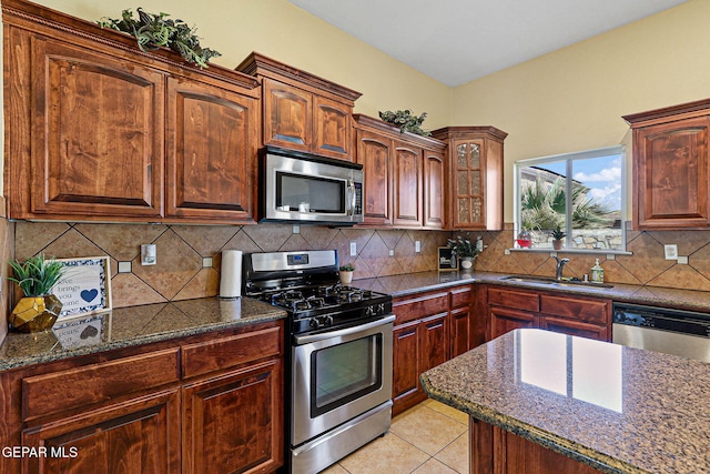 kitchen featuring dark stone counters, light tile patterned floors, a sink, and stainless steel appliances