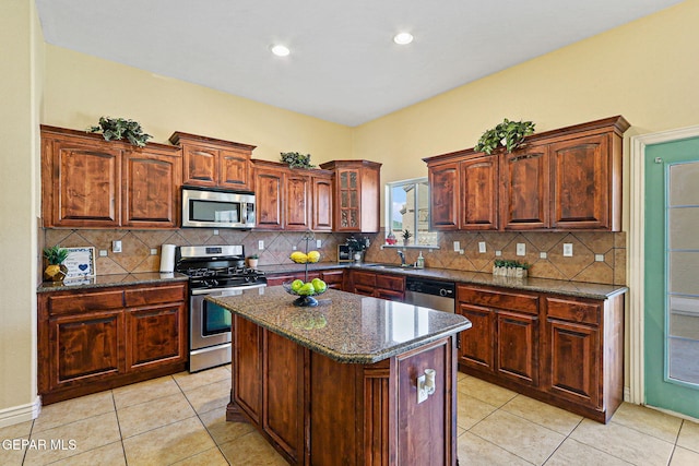 kitchen with tasteful backsplash, light tile patterned floors, stainless steel appliances, a center island, and dark stone counters
