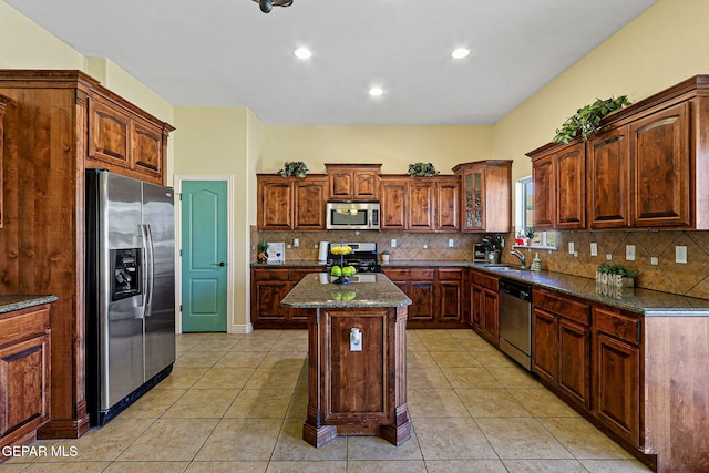 kitchen featuring backsplash, a sink, a center island, light tile patterned floors, and stainless steel appliances