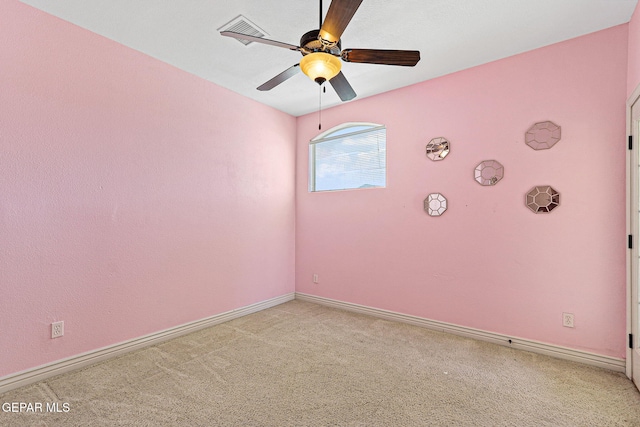 spare room featuring baseboards, ceiling fan, visible vents, and light colored carpet