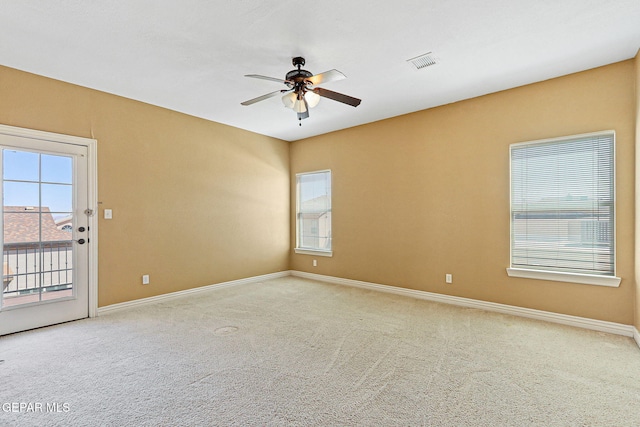 empty room with carpet floors, baseboards, visible vents, and ceiling fan