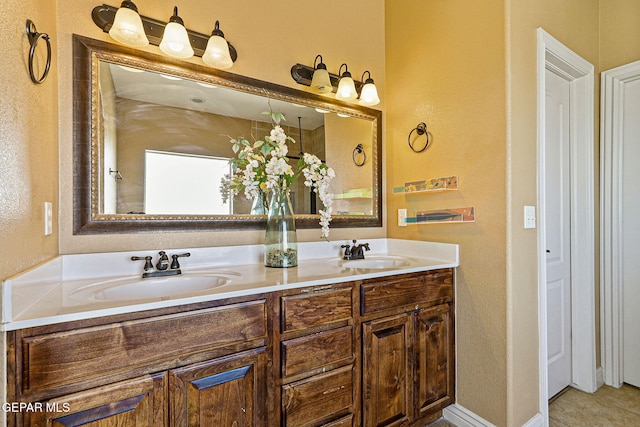 bathroom featuring double vanity, a sink, and baseboards
