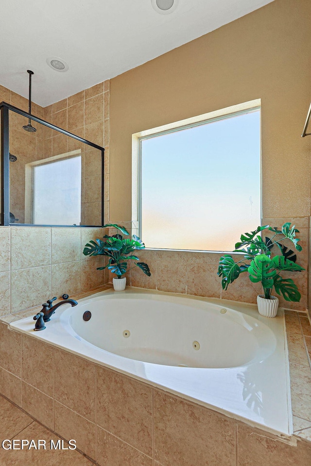 bathroom featuring a tub with jets and a tile shower