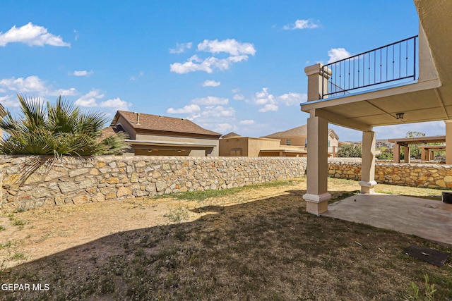 view of yard featuring a balcony, fence, and a patio