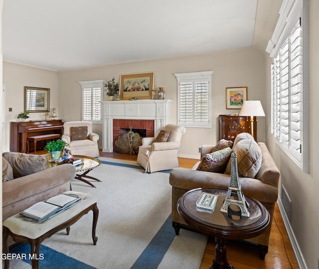 living room with baseboards, a fireplace, visible vents, and wood finished floors
