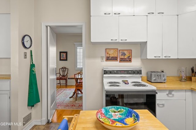 kitchen with white electric range oven, white cabinetry, visible vents, and butcher block countertops