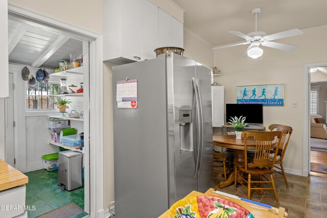 kitchen with a ceiling fan, white cabinetry, stainless steel refrigerator with ice dispenser, baseboards, and beamed ceiling
