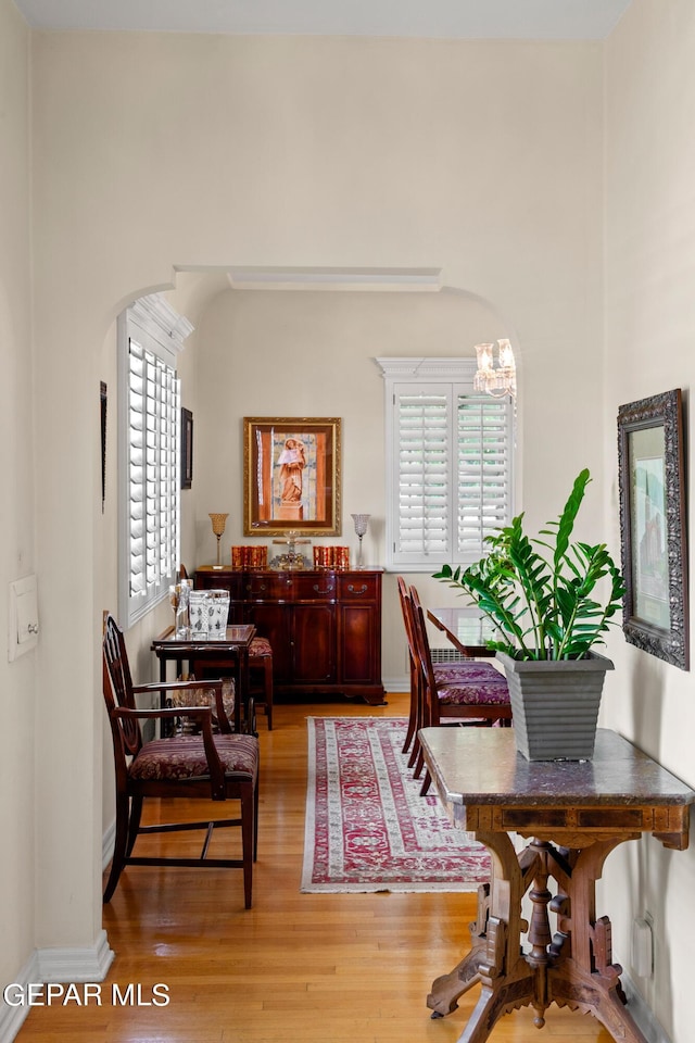 dining room featuring light wood finished floors, baseboards, arched walkways, and an inviting chandelier