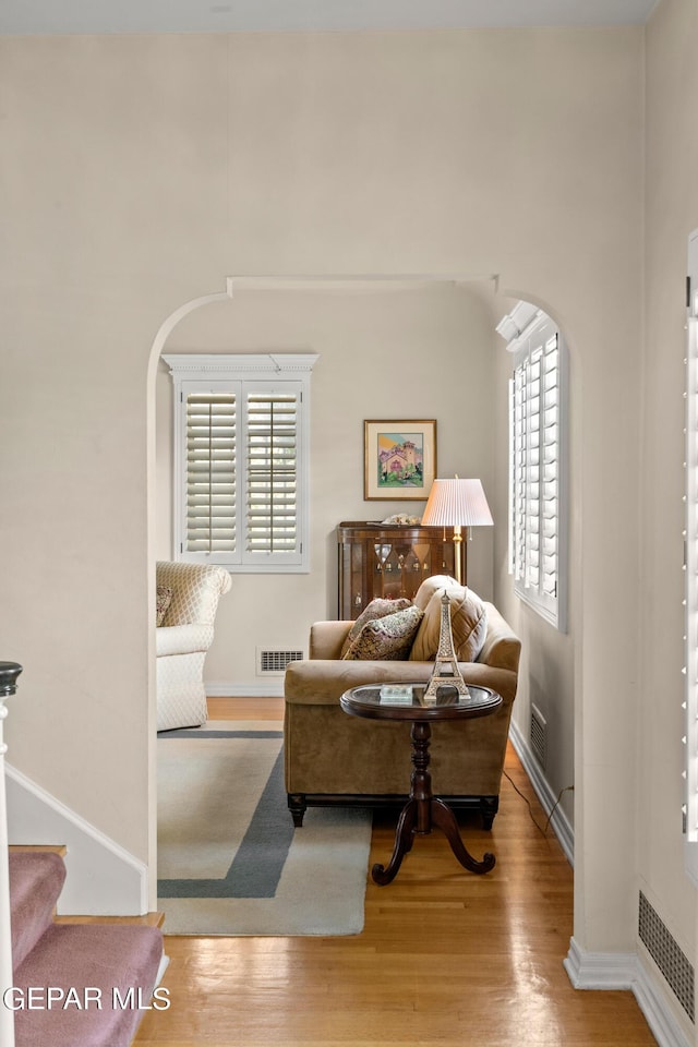 living area with arched walkways, visible vents, and wood finished floors