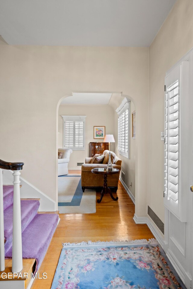 foyer featuring stairs, baseboards, arched walkways, visible vents, and wood finished floors