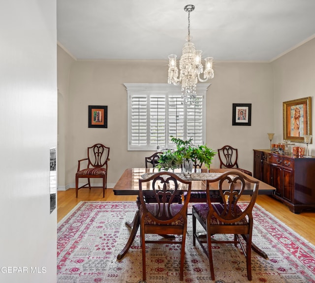 dining room featuring baseboards, light wood-style flooring, ornamental molding, and a chandelier