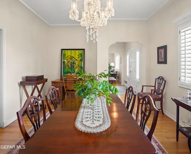 dining space with crown molding, wood finished floors, arched walkways, and a chandelier