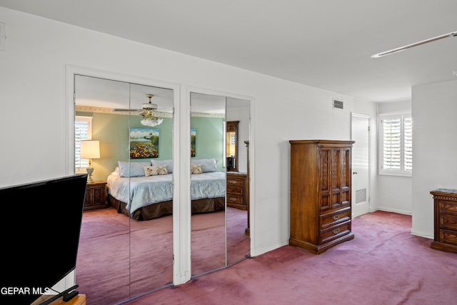 carpeted bedroom featuring baseboards, visible vents, and two closets