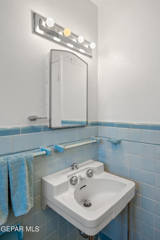 bathroom featuring a sink, tile walls, and wainscoting