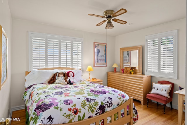 bedroom with light wood finished floors, baseboards, and ceiling fan