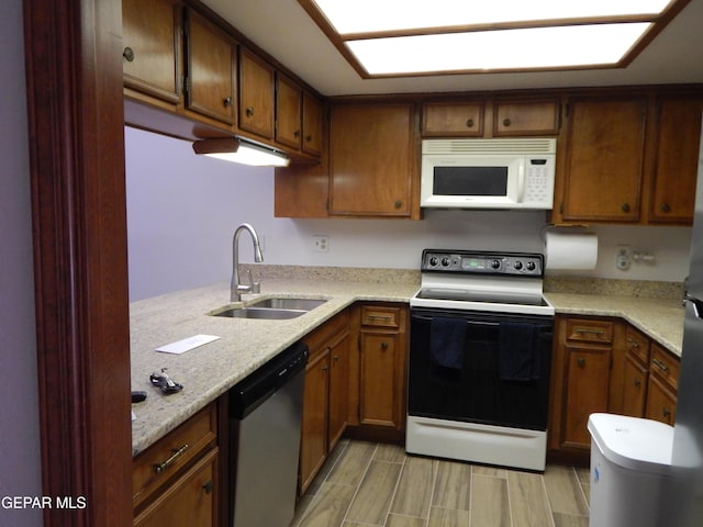 kitchen featuring dishwasher, a sink, light stone countertops, white microwave, and electric range